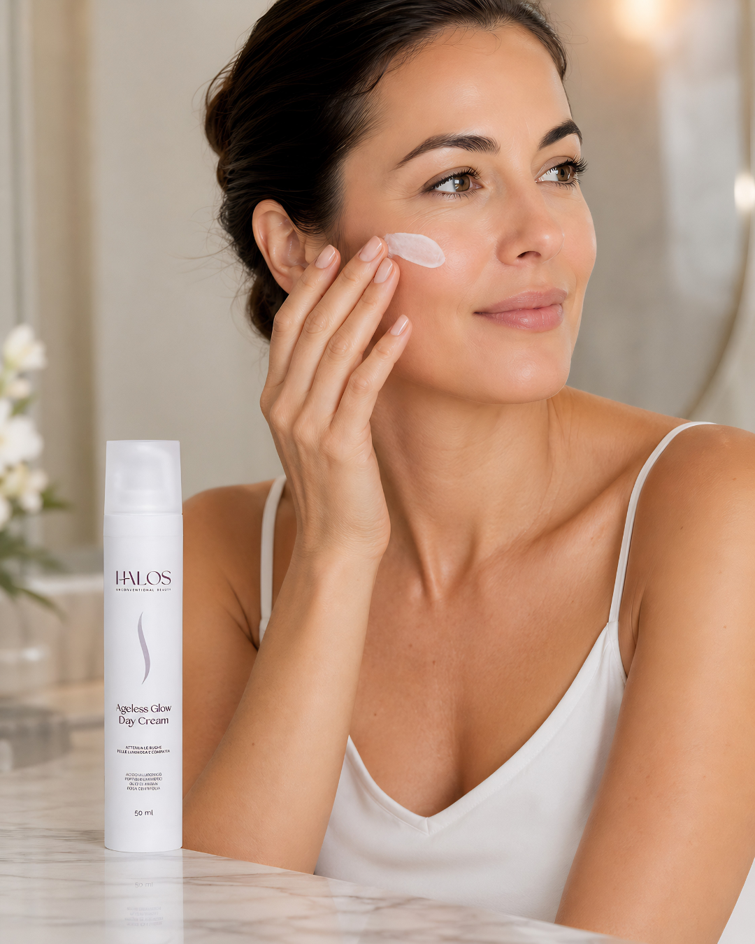 Donna che applica Ageless Glow Day Cream sulla guancia