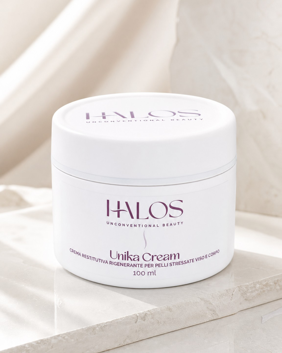 Vasetto di Unika Cream Halos, crema viso e corpo, su una base in pietra chiara