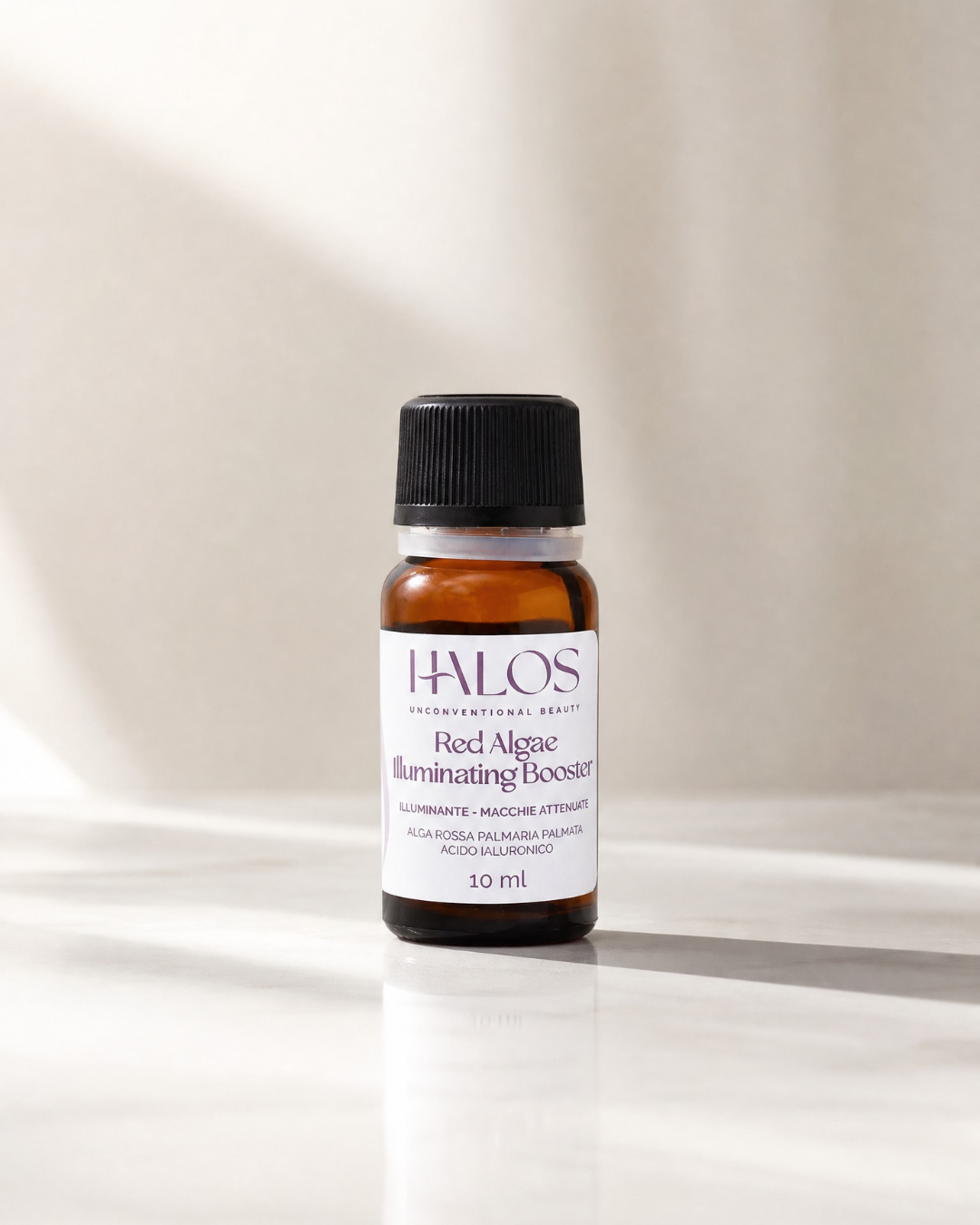 Flacone chiuso di Red Algae Illuminating Booster Halos su marmo chiaro