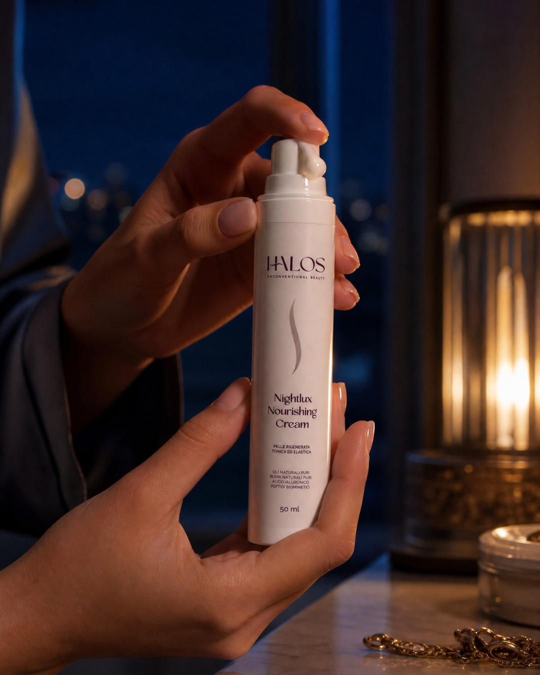 Mani che erogano Nightlux Nourishing Cream dal flacone airless durante il rituale serale